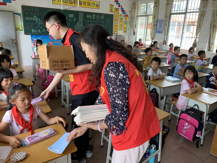 志愿者给学生们送上笔盒和本子.JPG