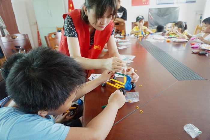 志愿者在认真的与小朋友一起制作手工汽车模型.jpg